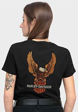 Woman stands backwards, showing the back of a shirt with a Harley-Davidson eagle logo.